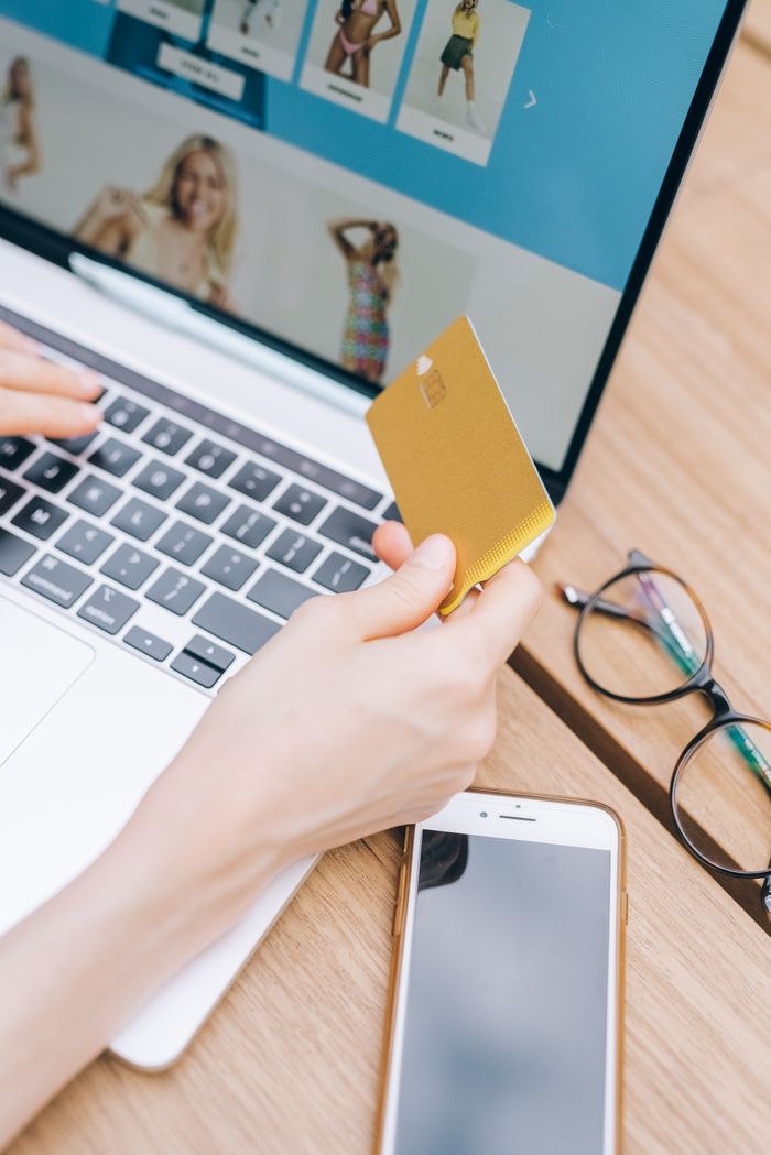 Close-up of a woman making an online purchase with a credit card on a laptop.