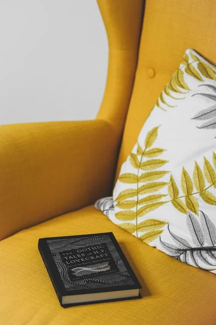 Des mains tenant une carte bancaire pendant un achat en ligne sur un ordinateur portable, posées sur une table en bois.