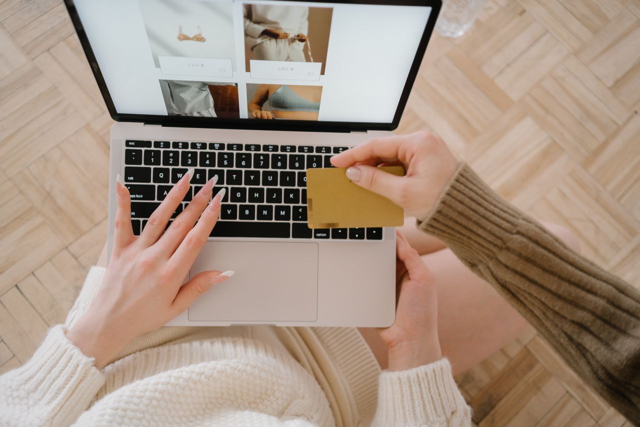 Une personne fait ses achats en ligne avec un ordinateur portable et une carte de crédit, mettant en avant la simplicité du e-commerce.