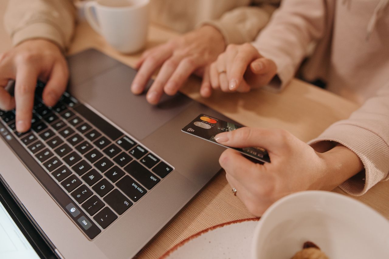 Close-up view of hands on a laptop while using a credit card to complete an online payment or shopping purchase.